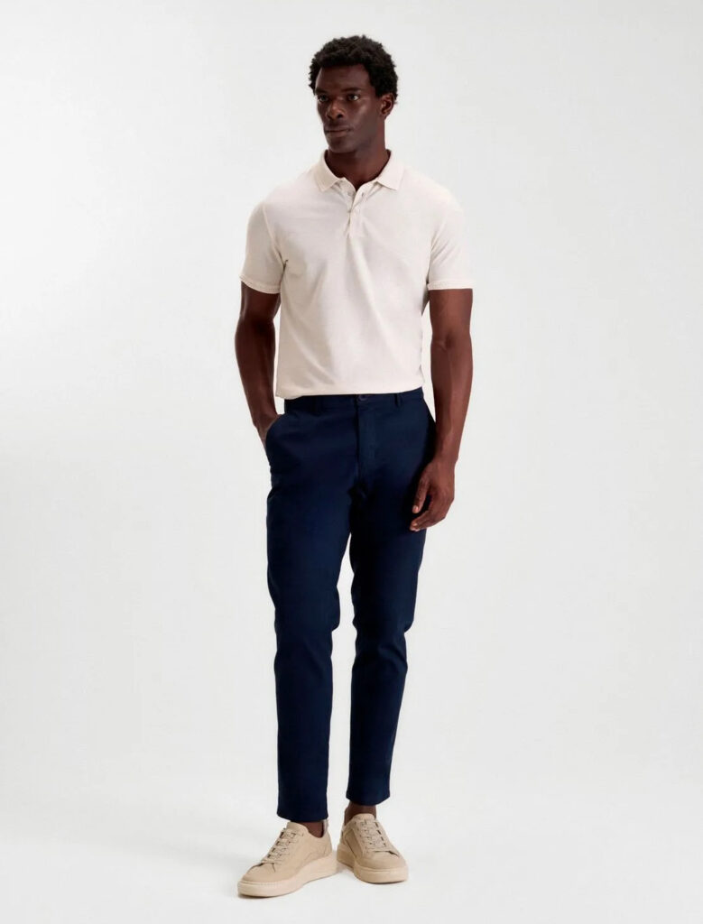 homem posa com calça de sarja masculina azul marinho e polo masculina