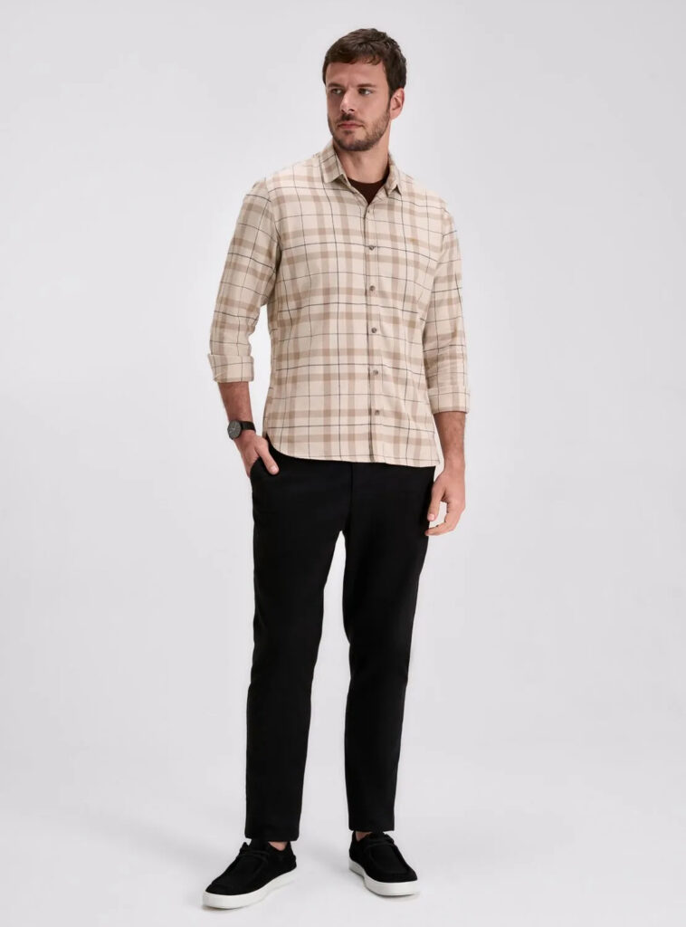 homem posa com calça de sarja masculina preta, sapato masculino preto e blusa masculina listrada
